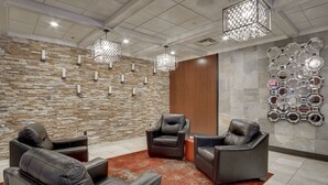 Una hall moderna con sedute in pelle, un tappeto decorativo e una parete con specchi esagonali.