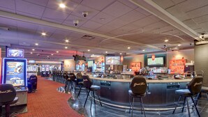Un'area bar di un casinò con diverse macchine da gioco, un bancone bar e vari sgabelli da bar.