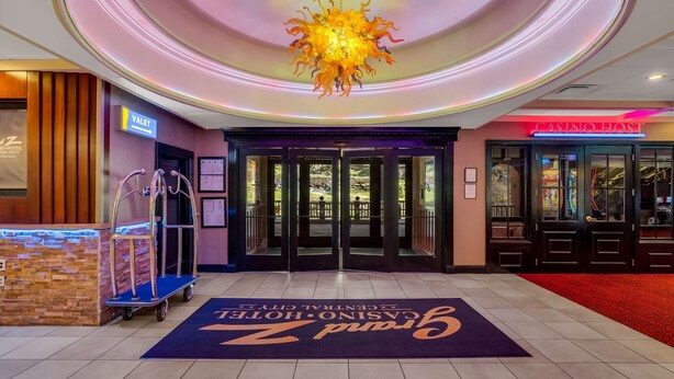 L'ingresso di un hotel con una porta girevole, un cartello per il servizio di facchino e un cartello per l'ospite del casinò.