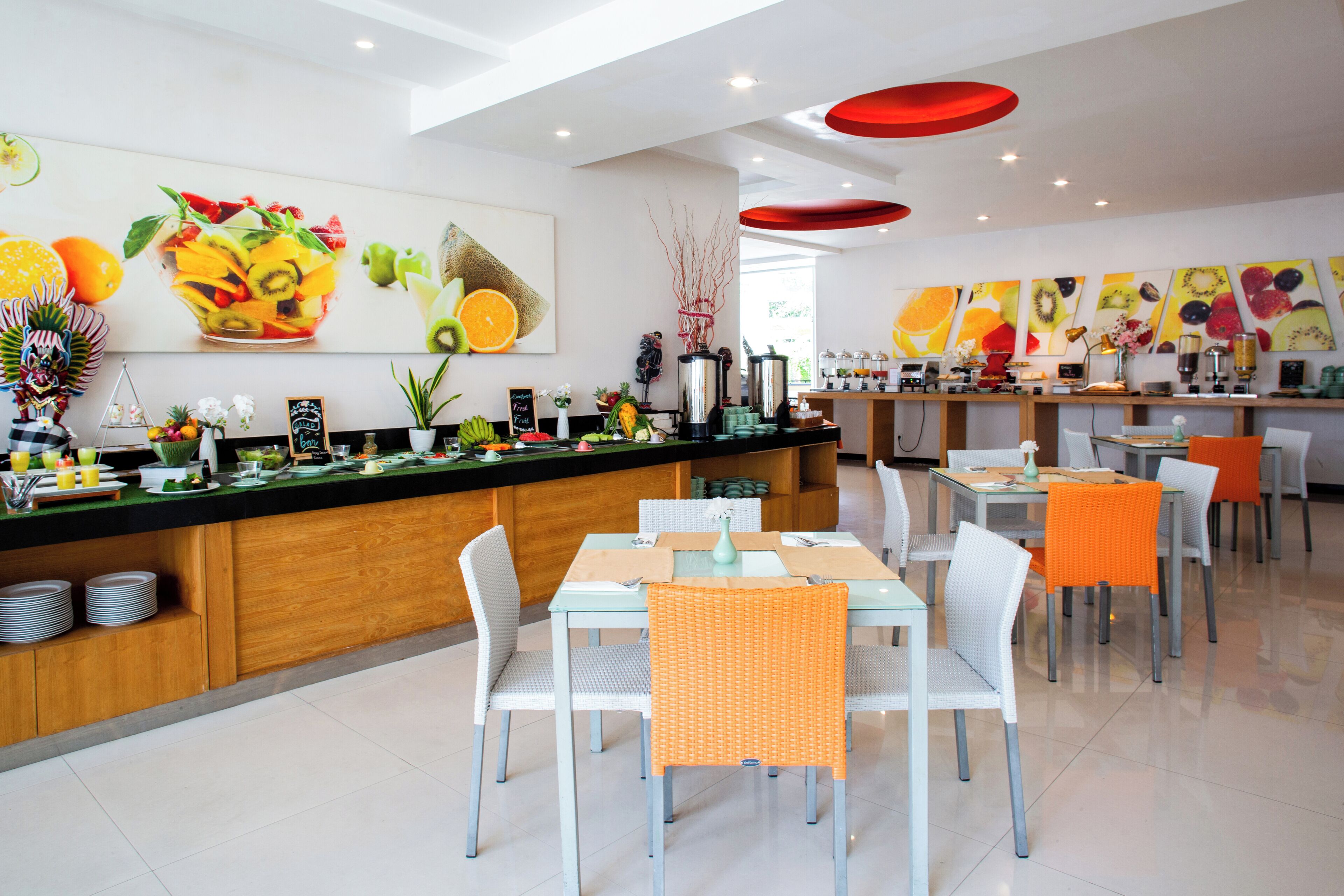A modern restaurant with a central counter, white chairs, and orange accents.