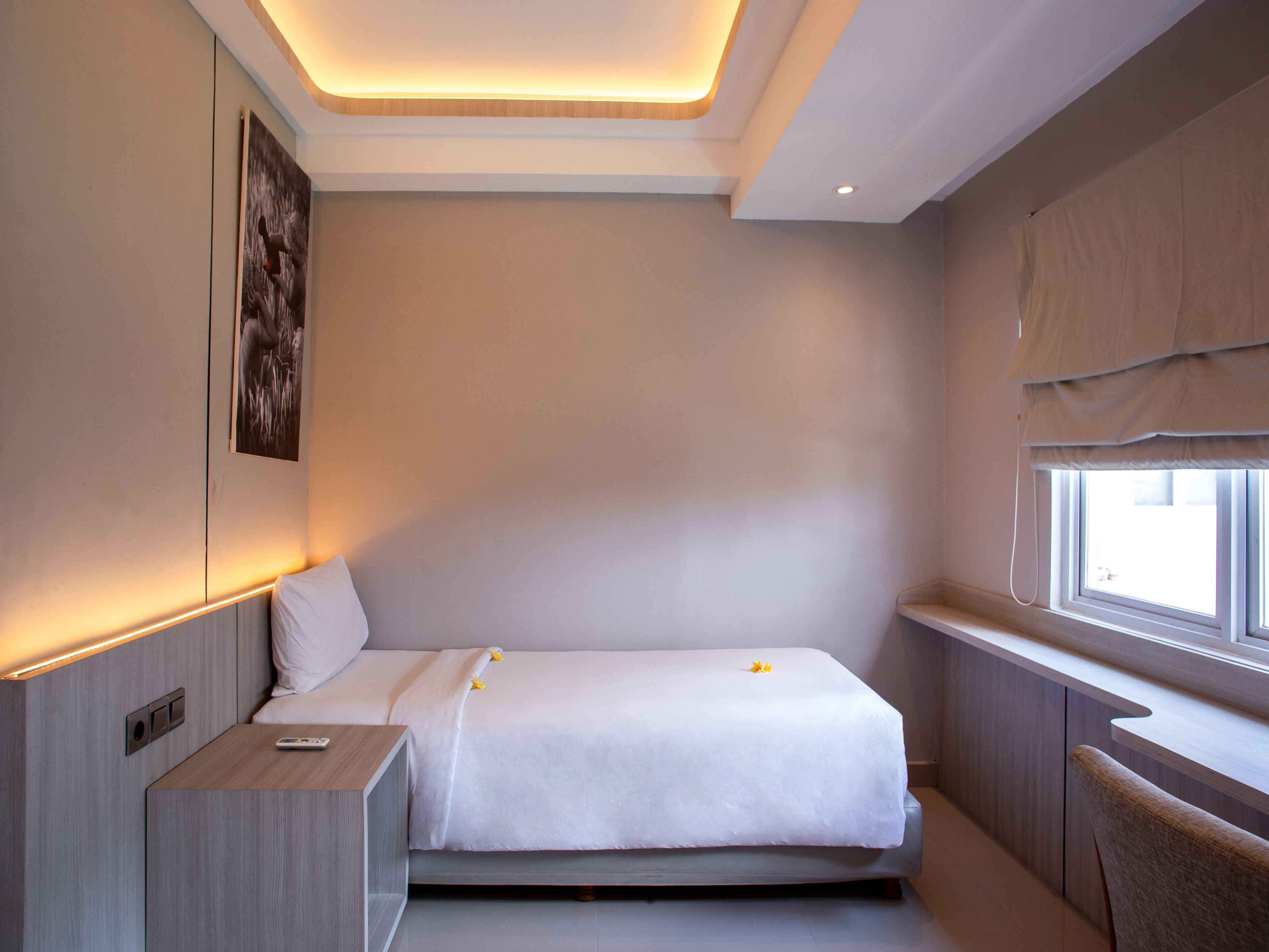 A modern hotel room with a bed, bedside table, and a window with curtains.