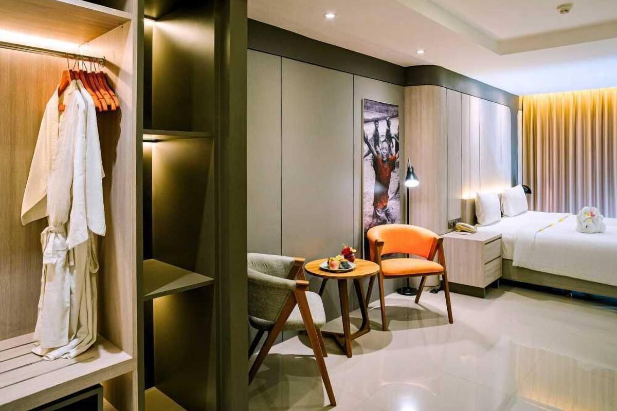 Ein modernes Hotelzimmer mit einem Bett, einer Sitzecke mit zwei Stühlen, einem kleinen Tisch und einem Kleiderschrank.