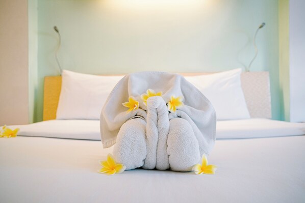 A neatly made bed with a towel shaped like a bunny and yellow flowers on it.