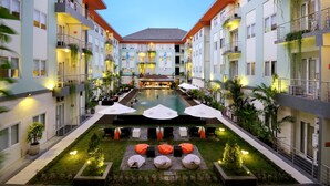Een hotel binnenplaats met een zwembad, terrasmeubilair en meerdere balkons.