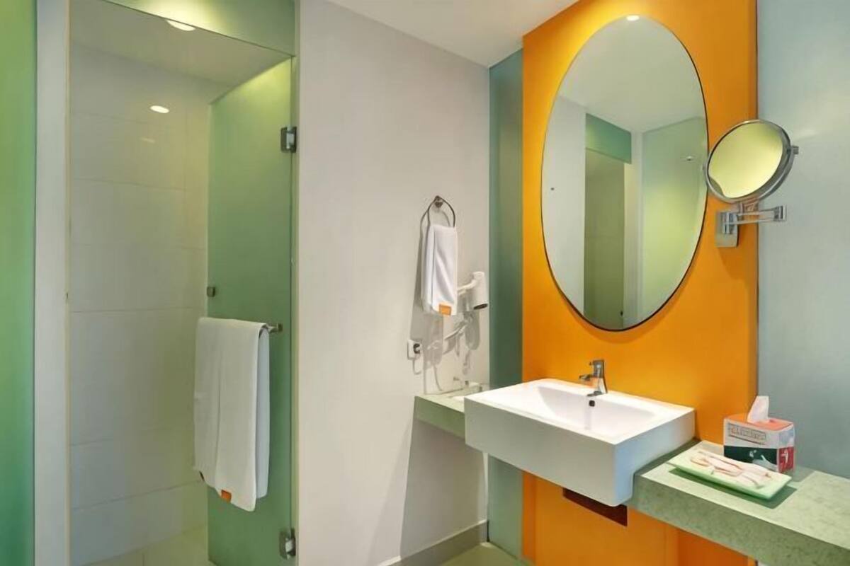 Ein Badezimmer mit Dusche, Waschbecken, Spiegel und Handtuchhalter.