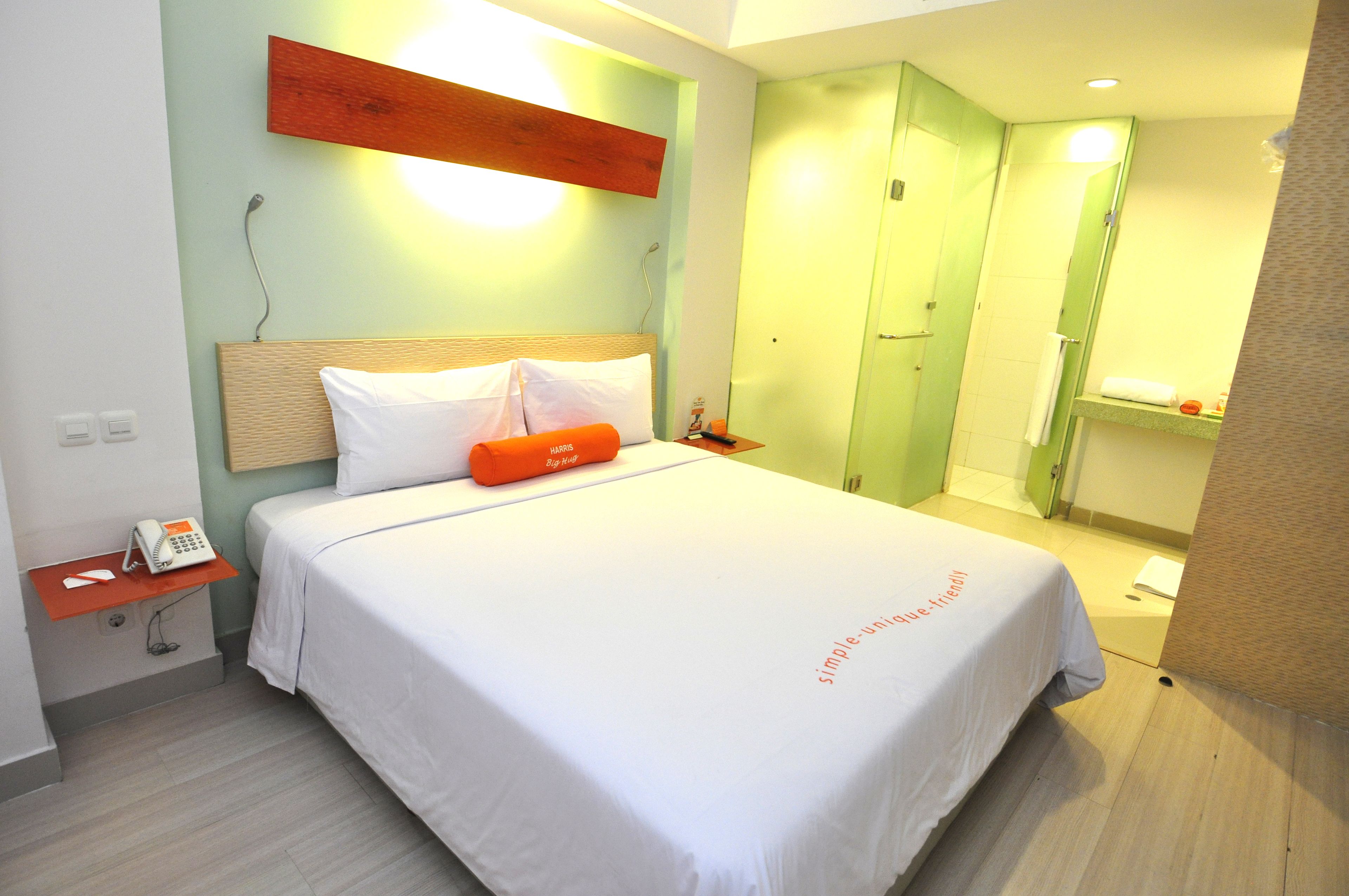 A hotel room with a bed, a nightstand with a phone, and a green wardrobe.