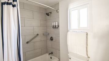 A bathroom with a bathtub, shower, and toilet.