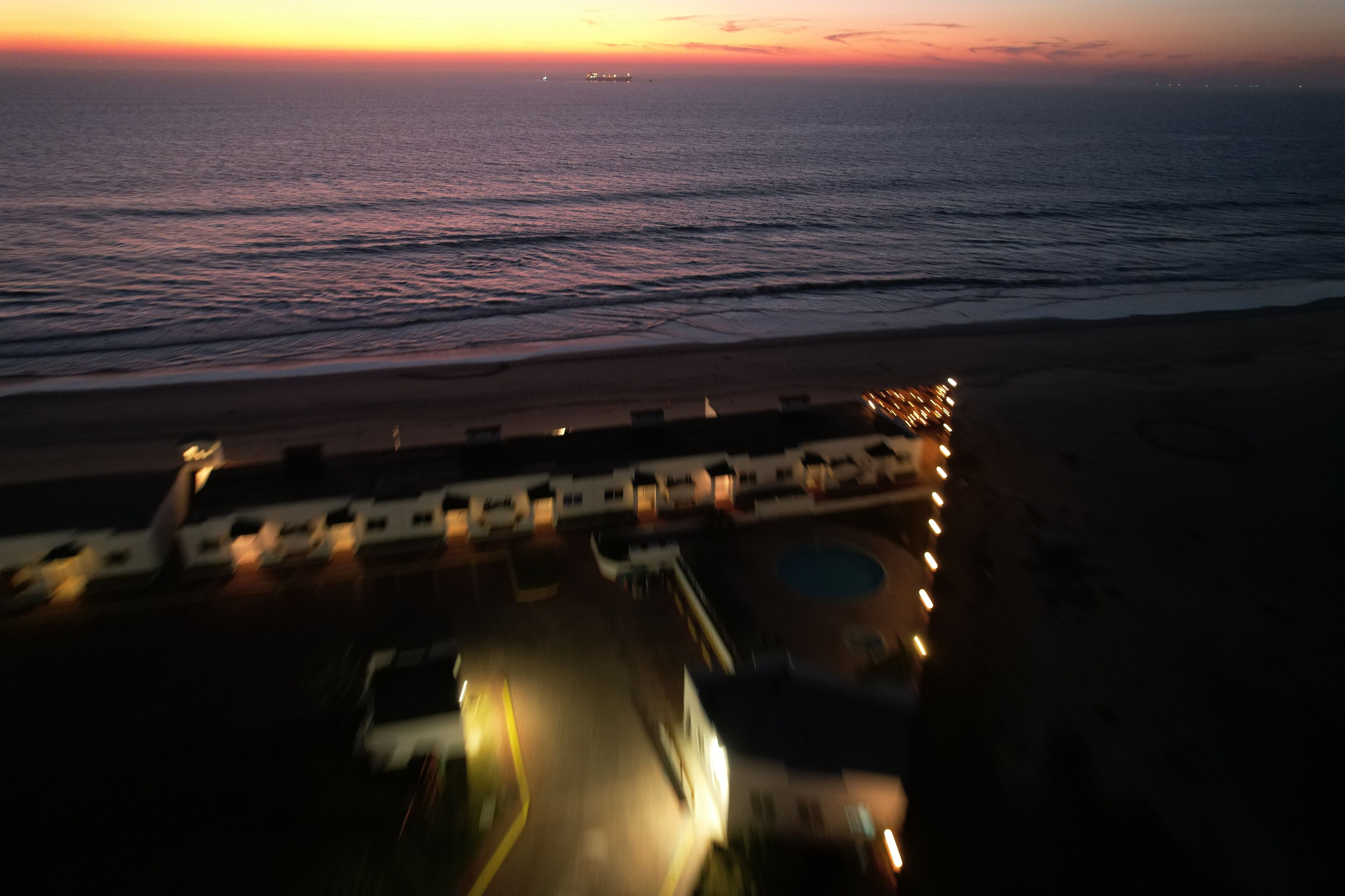 An aerial view of a coastal hotel with a beach in the background.