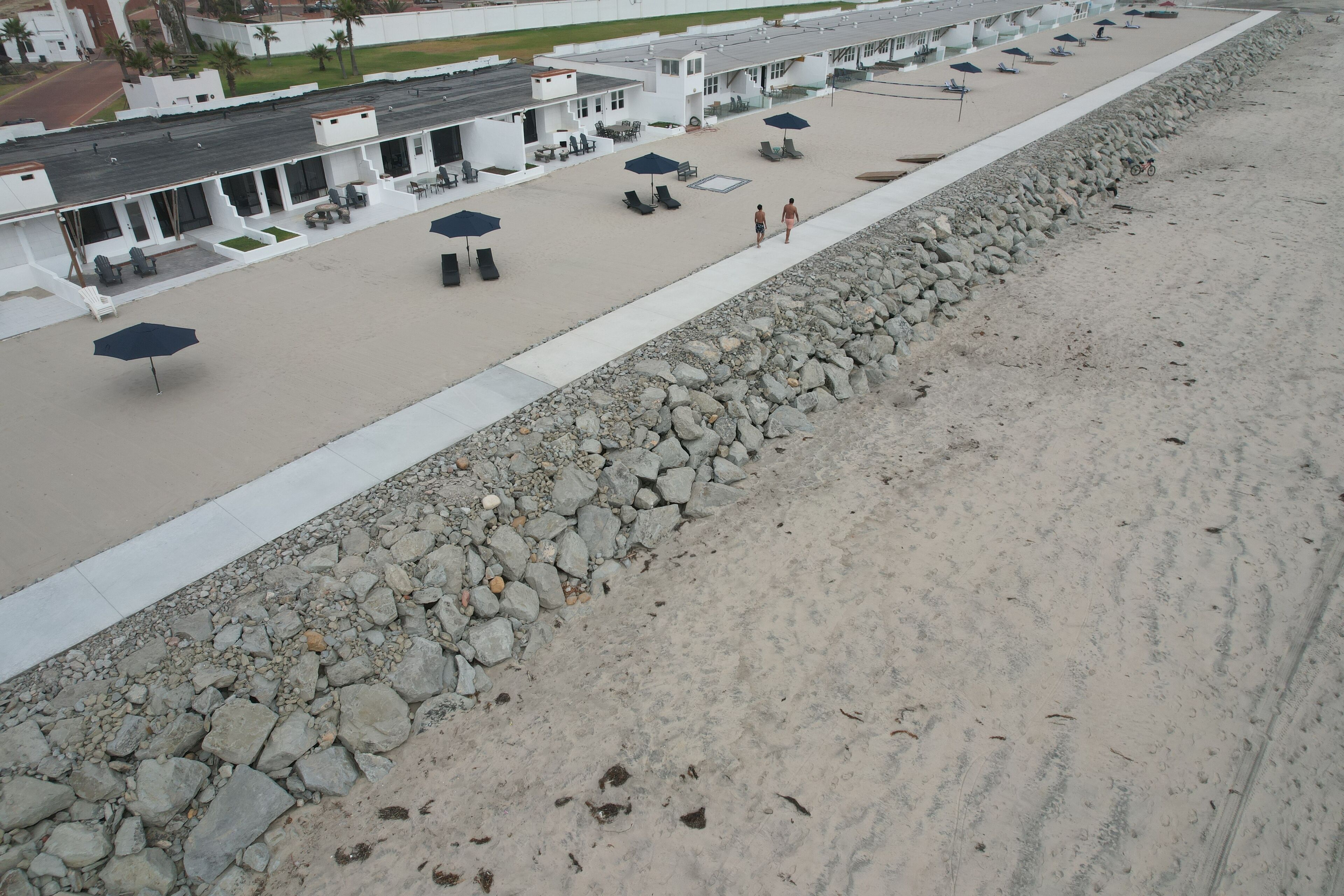 A beachside hotel with outdoor seating and umbrellas.