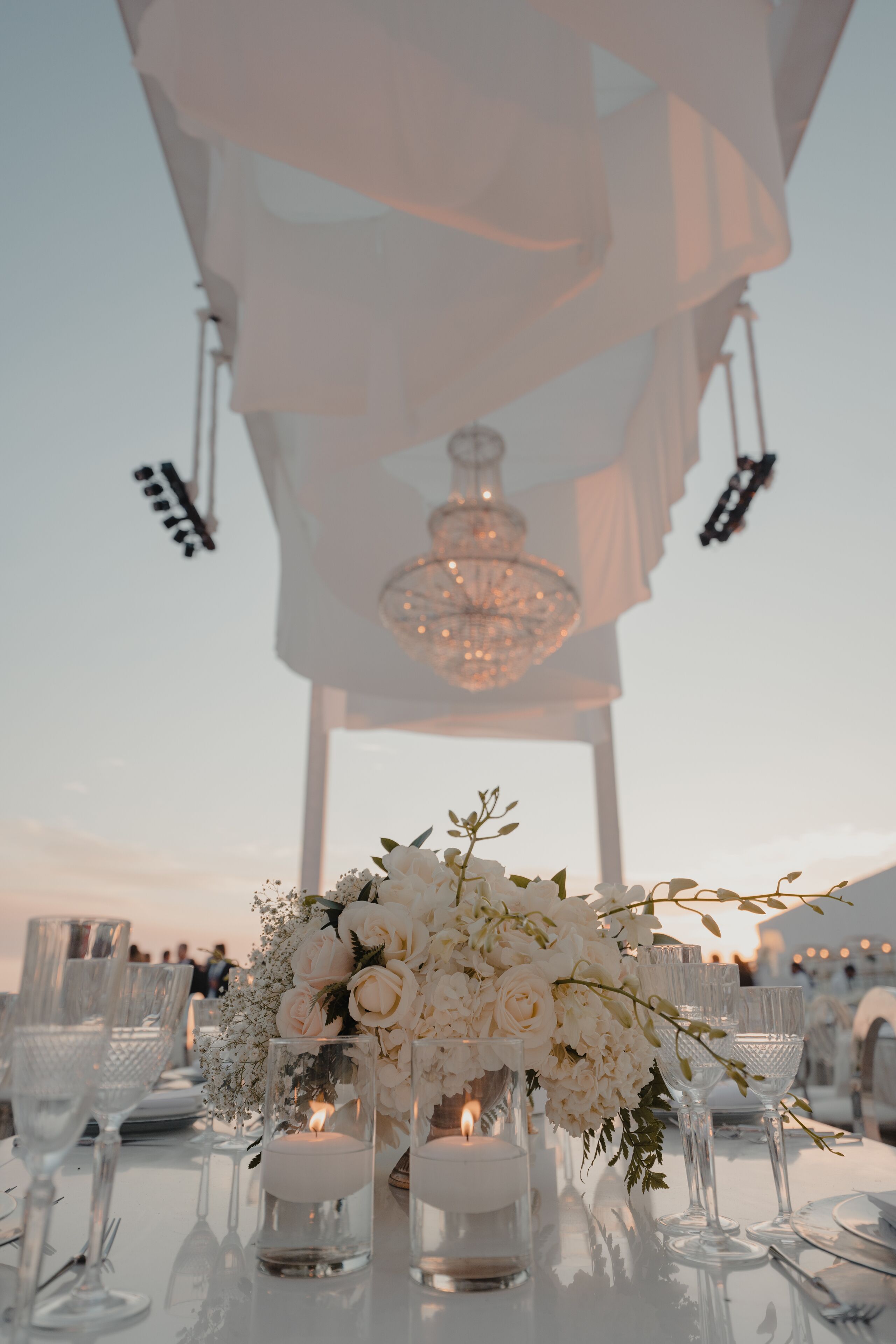 A table set for a formal event with white flowers, candles, and clear glassware.