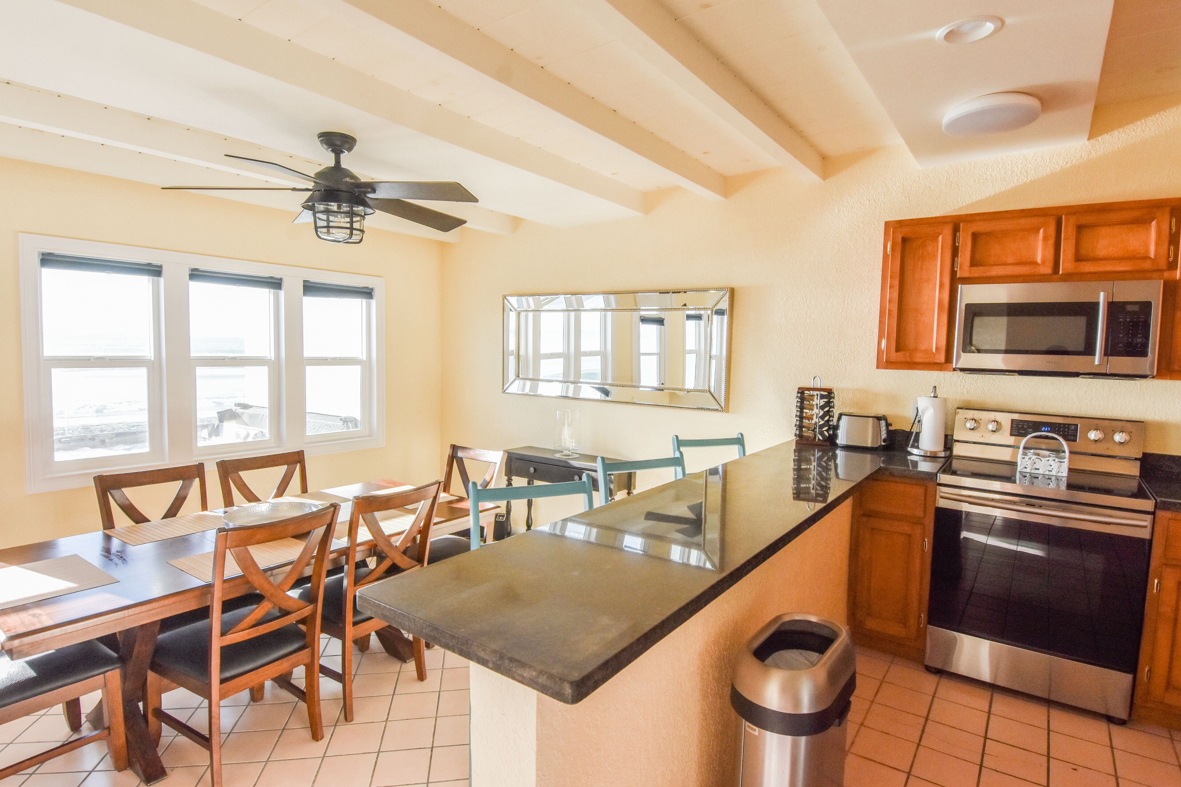A kitchen with wooden cabinets, a microwave, an oven, and a dining area with a table and chairs.