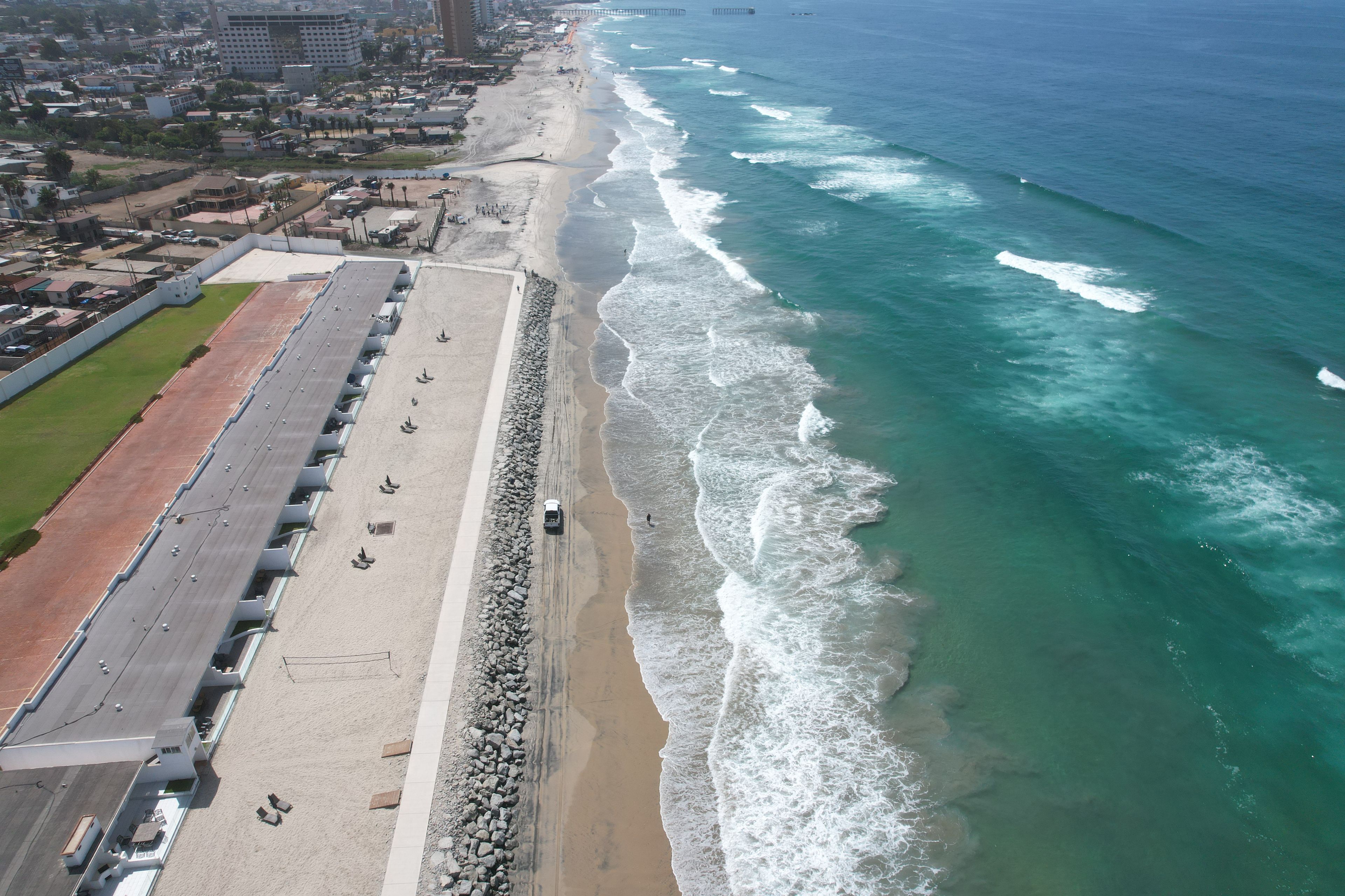 A coastal area with a long promenade, a sandy beach, and the ocean.