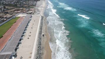 A coastal area with a long promenade, a sandy beach, and the ocean.