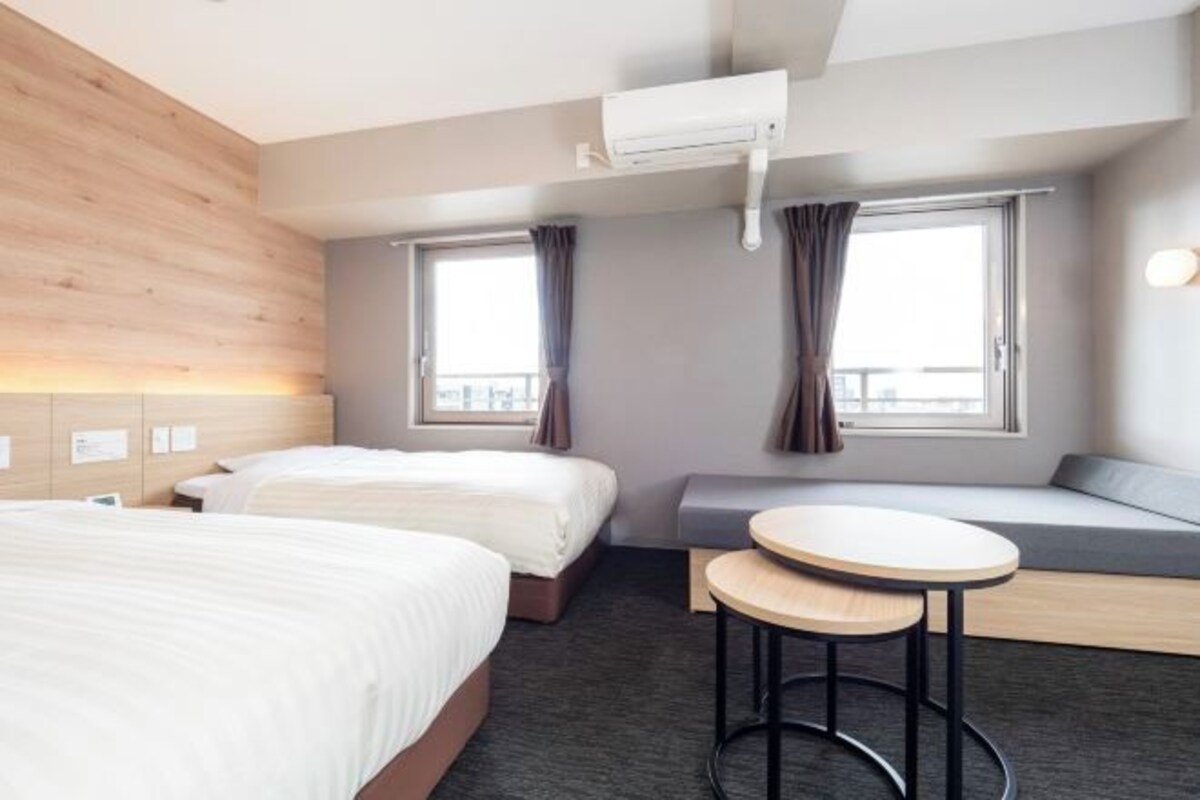 Una habitación de hotel con dos camas, una zona de estar y una mesita.