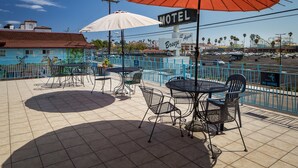A motel with outdoor seating and umbrellas, a sign indicating 'No Diving', and a view of a parking lot and distant buildings. - Aqua Breeze Inn (Santa Cruz)