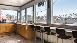 A kitchen with a bar area, large windows, and a view of the street. - Aqua Breeze Inn (Santa Cruz)