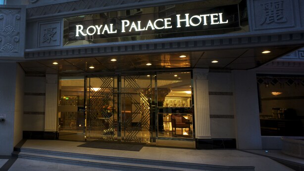 The exterior of the Royal Palace Hotel with its illuminated sign, large glass entrance, and ornate architectural details. - Royal Palace Hotel (Taipei)