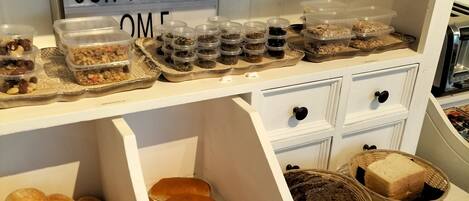 Mostrador de una panadería con diversos productos horneados y recipientes con alimentos.