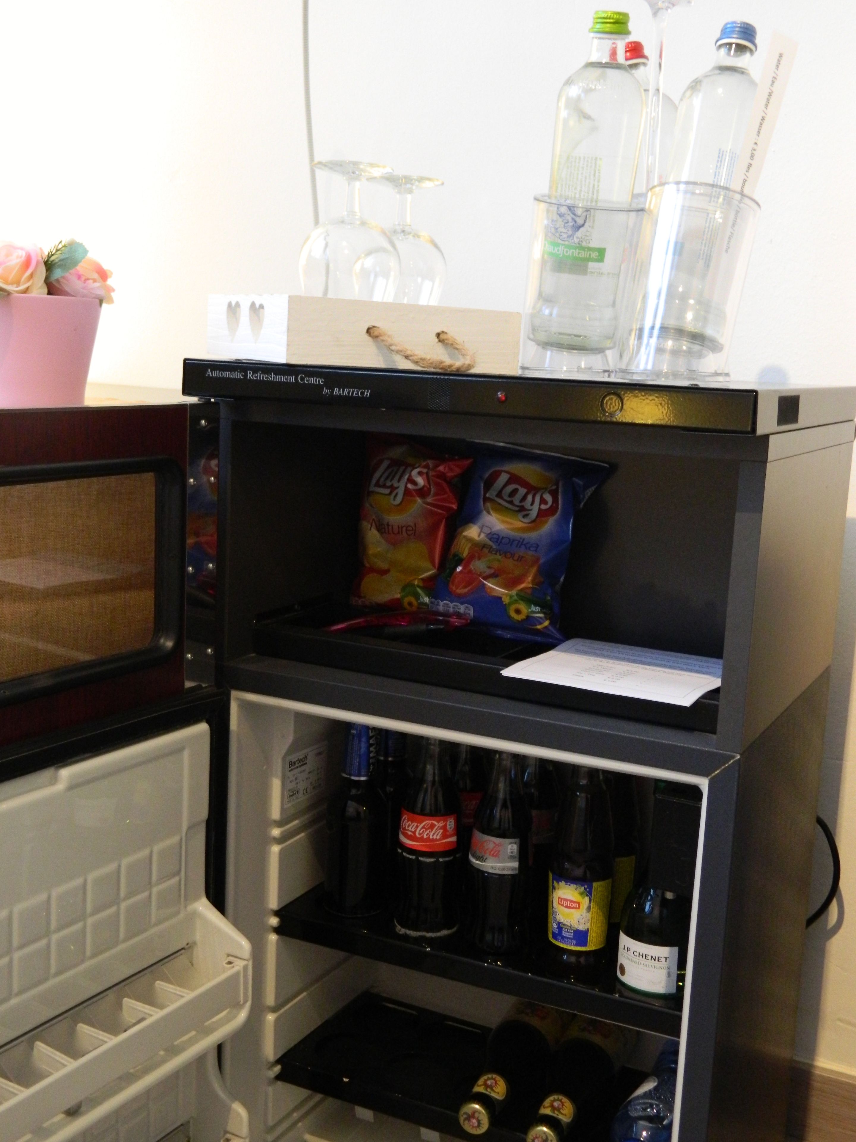 Un mini-bar contenant des en-cas, de l’eau en bouteille et des boissons alcoolisées.