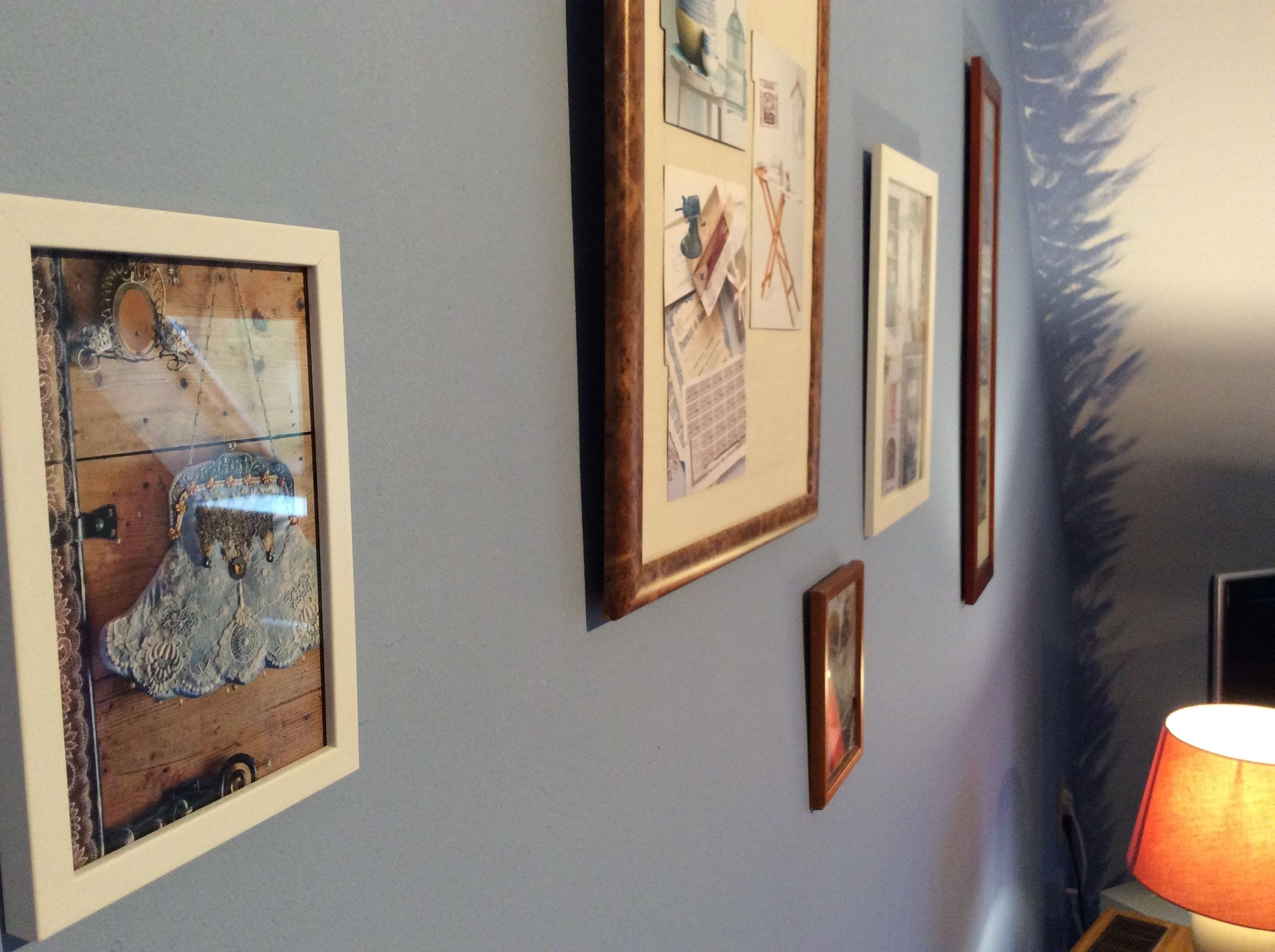 A wall with several framed pictures, a lamp, and a decorative mirror.