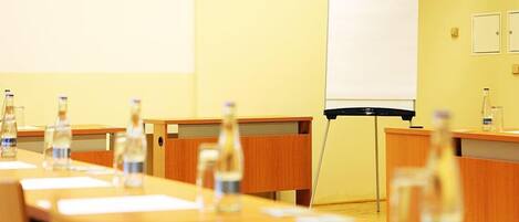 A conference room with a long table, chairs, a projector screen, and water bottles.