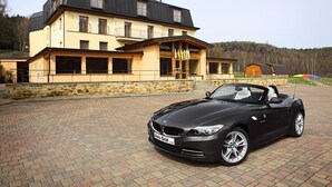 A hotel with a black BMW convertible parked in front. - Hotel Ostrov (Tisa)