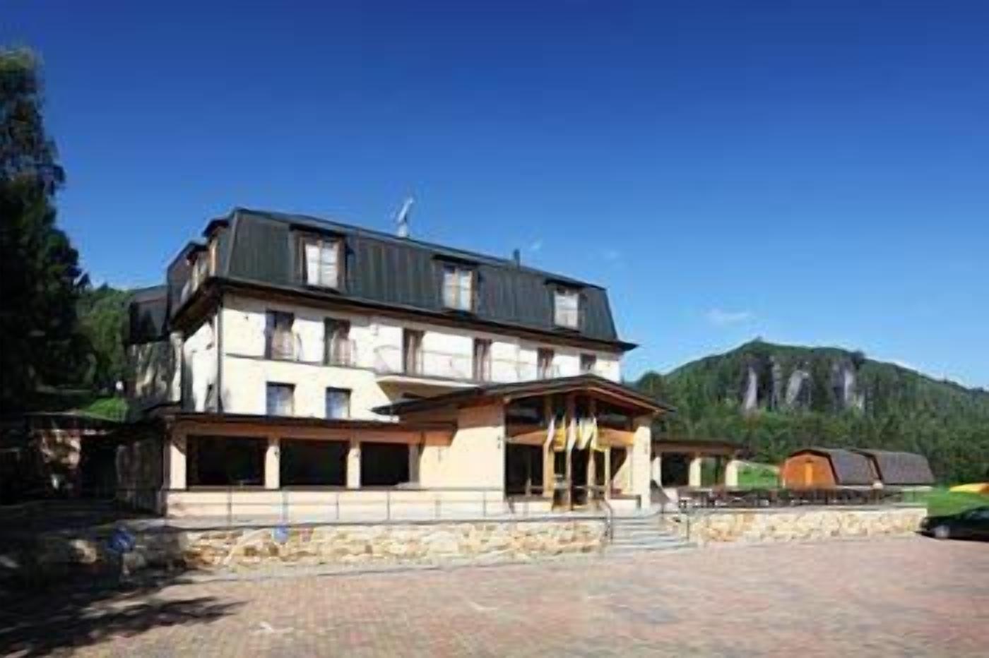 A large, multi-story building with a prominent entrance and a mountain backdrop.