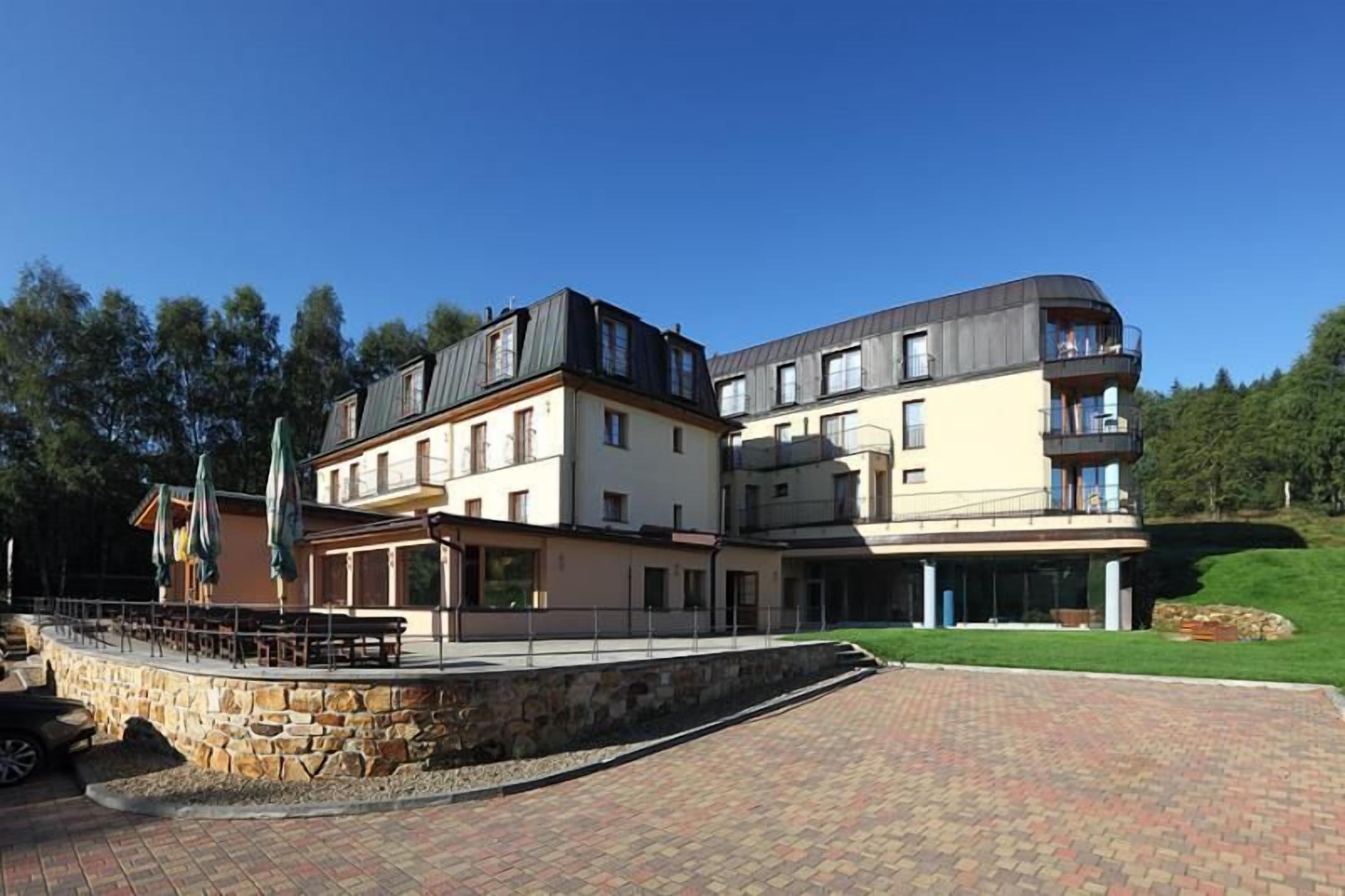 A multi-story hotel with a stone facade, outdoor seating area, and a paved walkway.