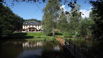 Hotel aan het meer met een houten terras en een brug.