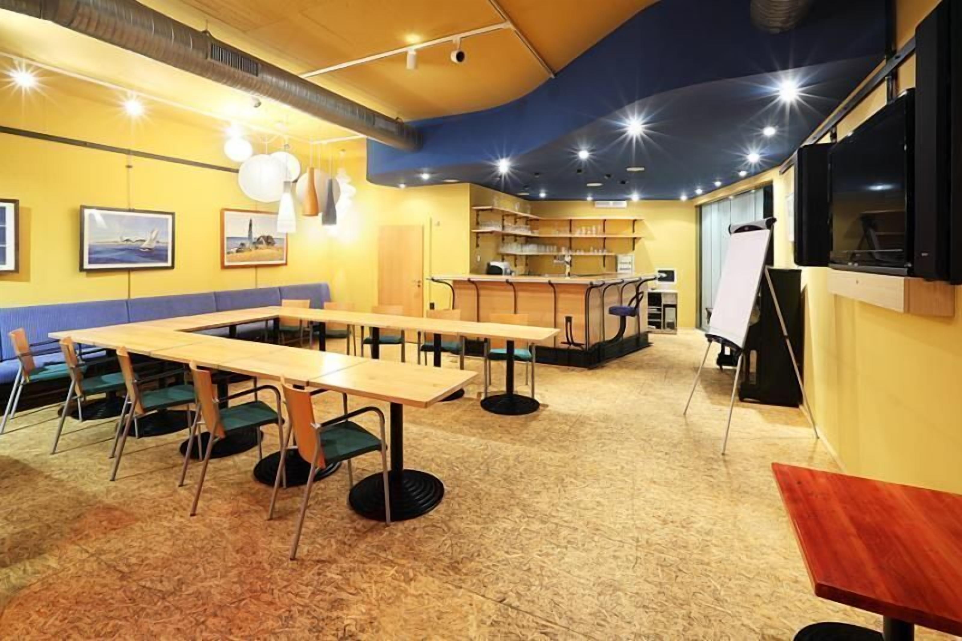 Ein Konferenzraum mit einem langen Tisch, Stühlen, einer Whiteboard und Regalen mit Büchern.