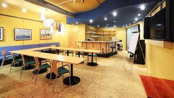 Ein Konferenzraum mit einem langen Tisch, Stühlen, einer Whiteboard und Regalen mit Büchern.