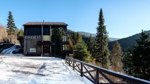 Un edificio con un letrero que dice "ONDRAS" en un paisaje nevado, con árboles y montañas al fondo.
