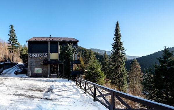 Un edificio con un letrero que dice "ONDRAS" en un paisaje nevado, con árboles y montañas al fondo.