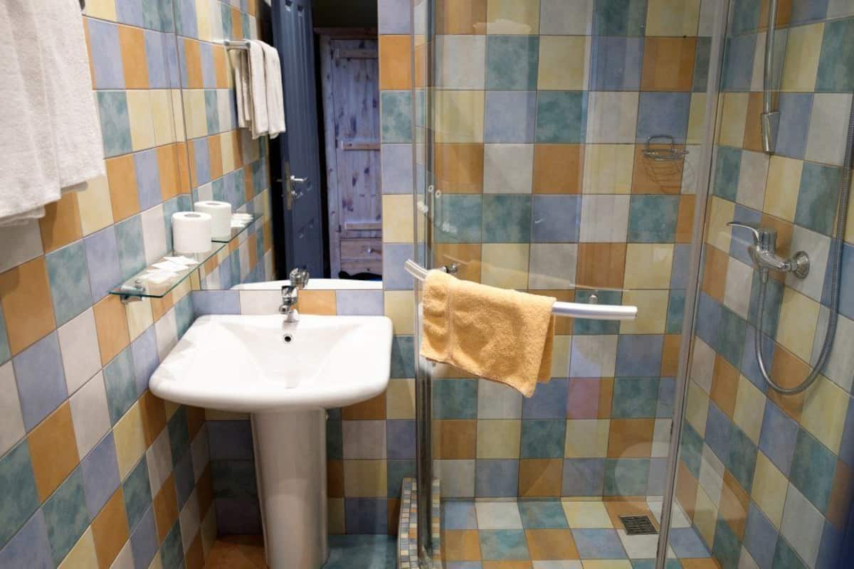 Ein Badezimmer mit Fliesenboden, einem Waschbecken, einer Duschkabine aus Glas und einem Handtuchhalter.