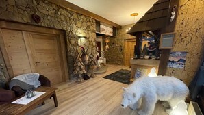 A cozy interior with a stone wall, wooden furniture, and a white dog. - Hôtel les Glaciers (Samoëns)
