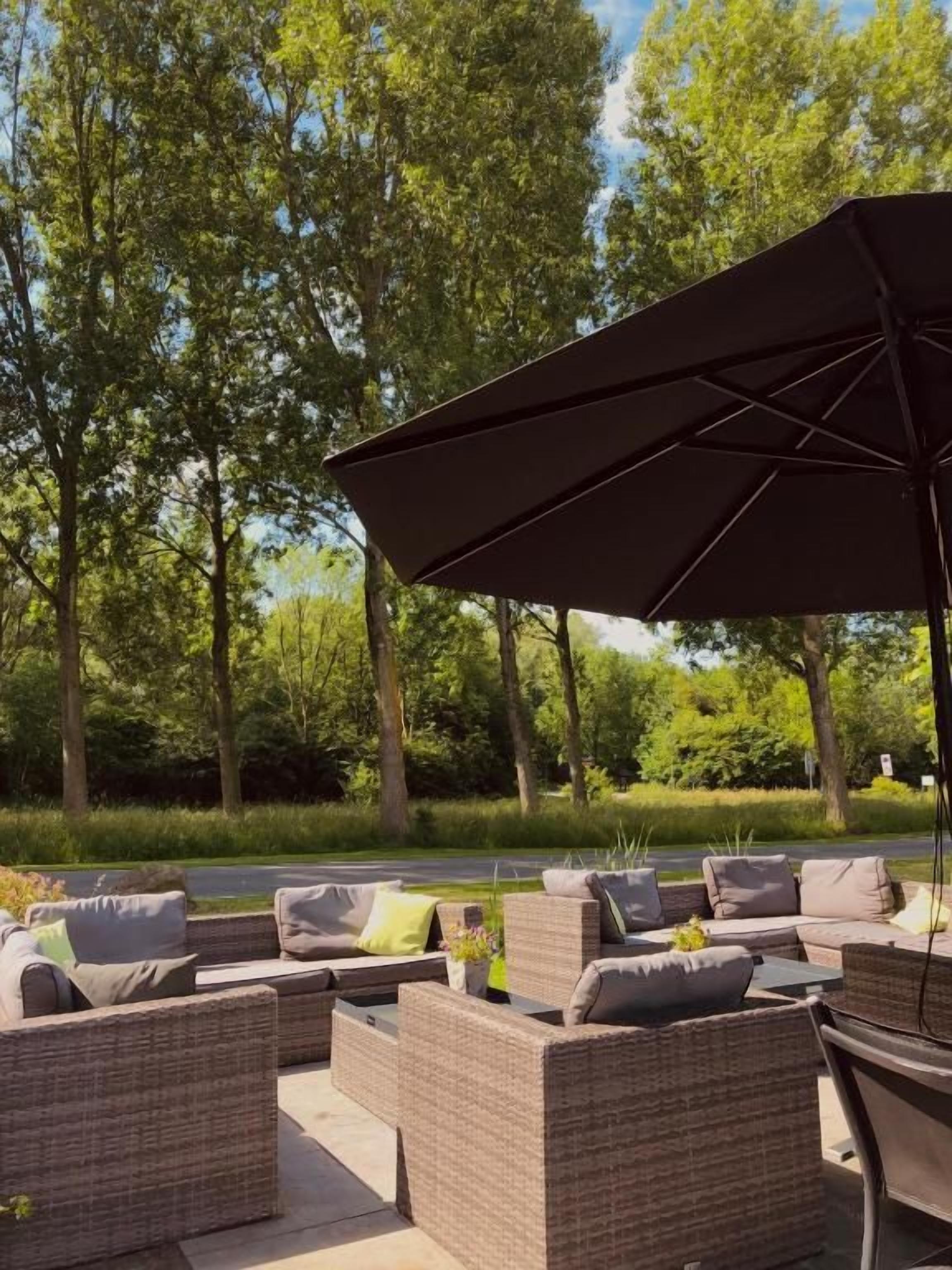 Un área de estar al aire libre con muebles de mimbre y un paraguas grande.