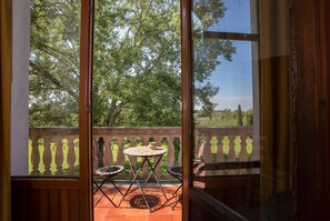 A balcony with a table and chairs, a view of trees and a distant building. - Lato Azzurro (Venice)