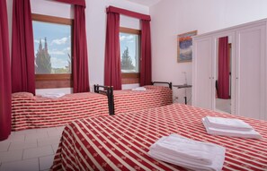 A hotel room with two beds, red and white striped bedding, a wooden headboard, a window with red curtains, and a painting on the wall. - Lato Azzurro (Venice)