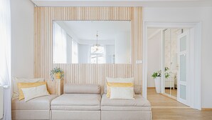 A modern living room with a beige sofa, a large mirror, and wooden paneling on the wall. - Boutique Pension Ametyst (Cesky Krumlov)