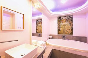 Une salle de bain moderne dotée d’une grande baignoire, d’un meuble-lavabo et de deux miroirs fixés au mur.