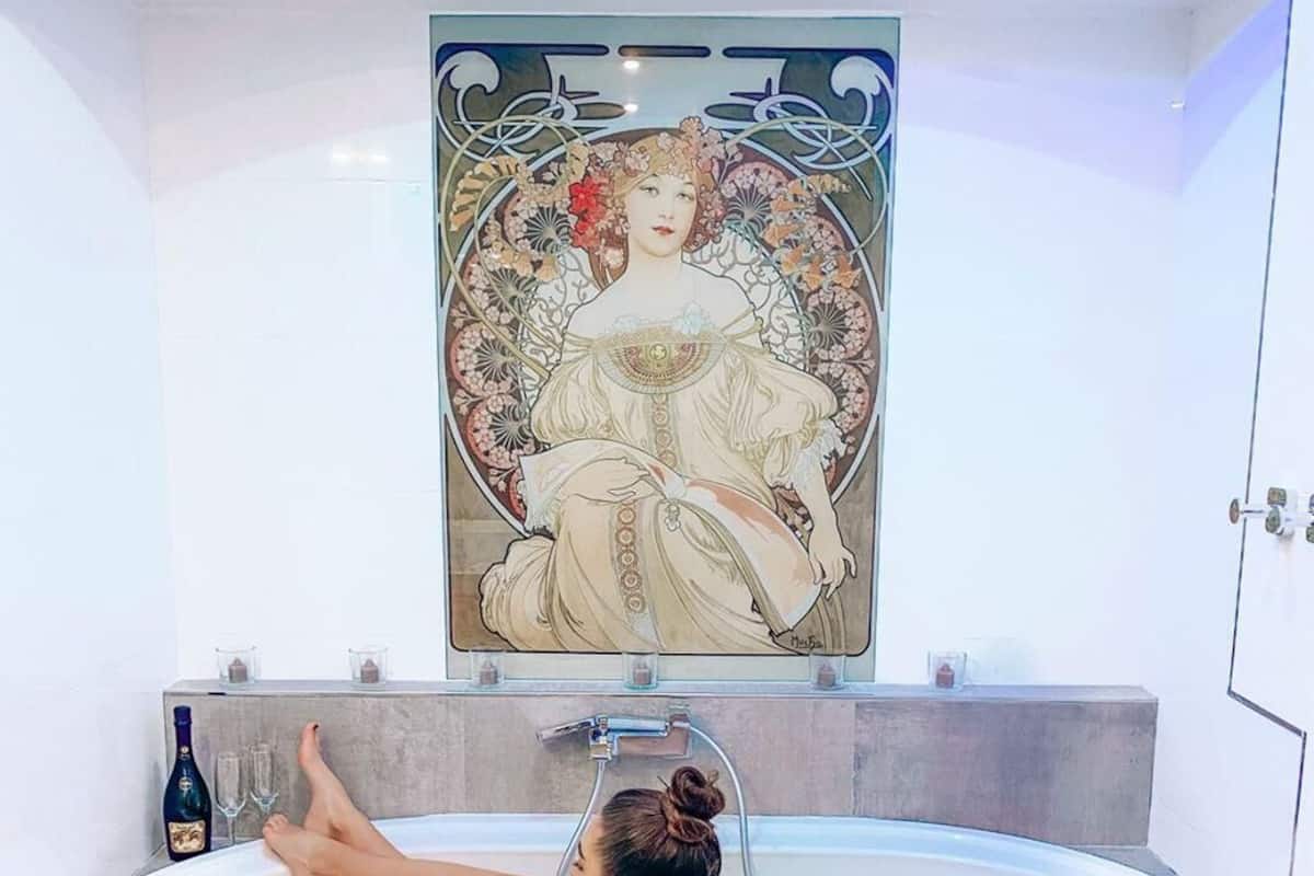 A woman relaxing in a bathtub with a decorative wall mural above.