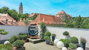A rooftop garden with potted plants, a unique chair, and a view of historic buildings. - Boutique Pension Ametyst (Cesky Krumlov)