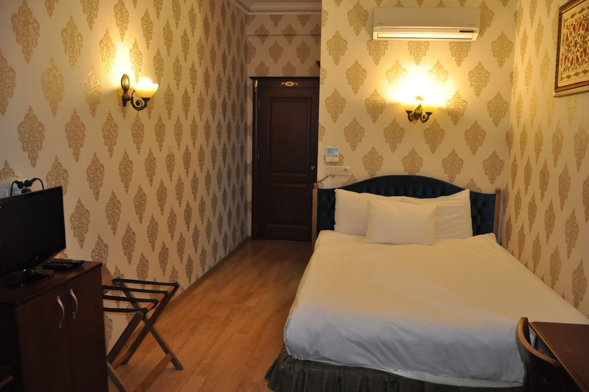 A hotel room with a bed, a TV, a desk, and a wardrobe.