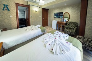 A hotel room with two beds, a desk, a chair, a mirror, and a television.