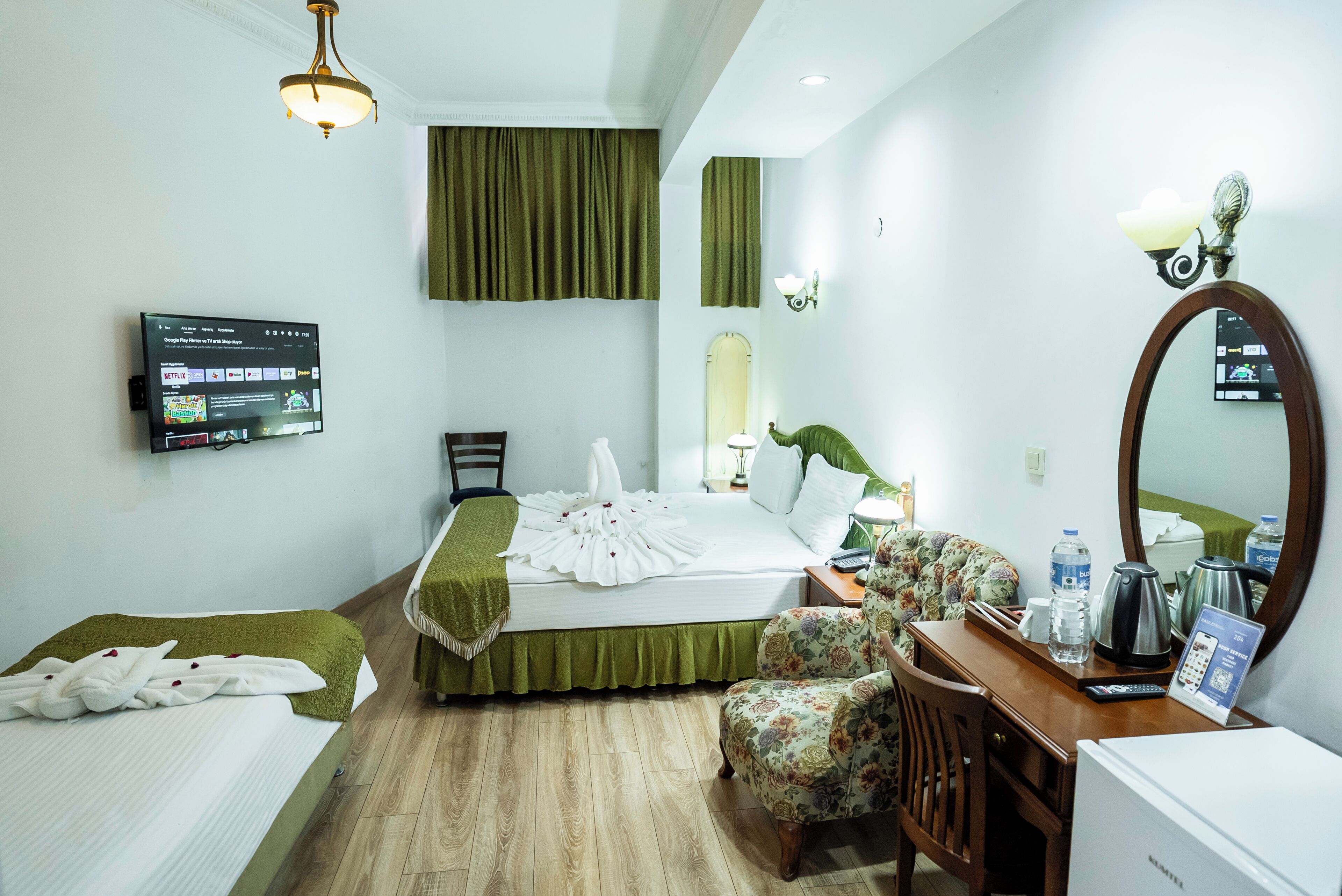 A hotel room with a bed, a desk with a chair, a television, and a mirror.