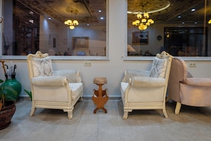 A room with two upholstered armchairs, a small wooden side table, and a large green vase. - Basileus Hotel (Istanbul)
