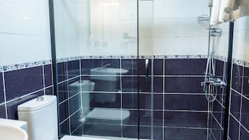 A modern bathroom with a glass-enclosed shower, a toilet, and a sink.