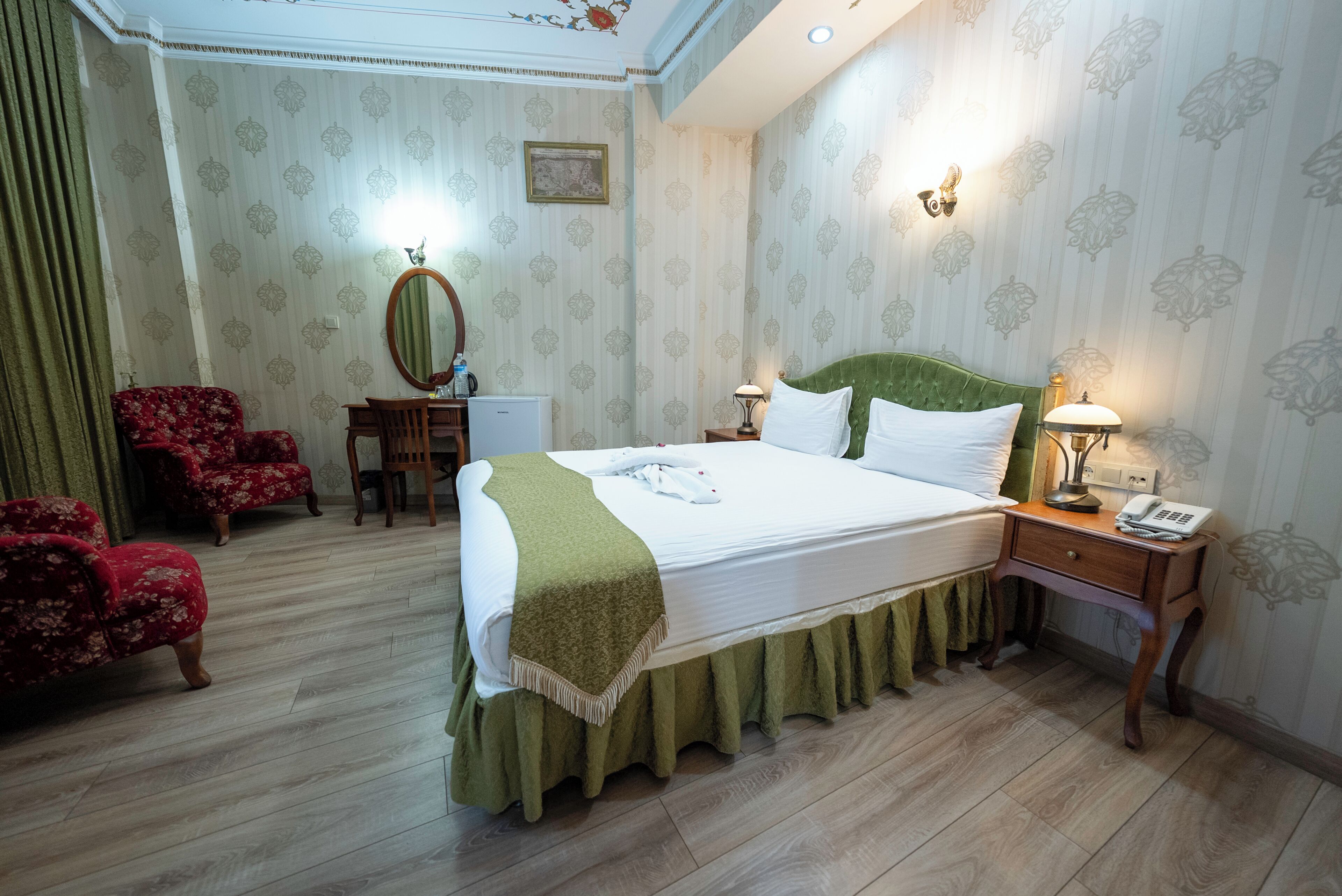 A hotel room with a bed, a desk, a chair, and a telephone.