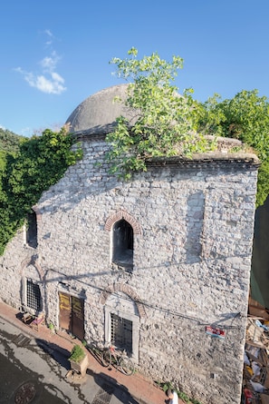 A stone building with a dome, arched windows, and a small door.