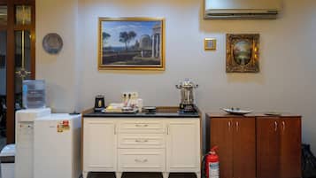 A kitchen with a refrigerator, a water dispenser, a coffee maker, a blender, and a fire extinguisher.